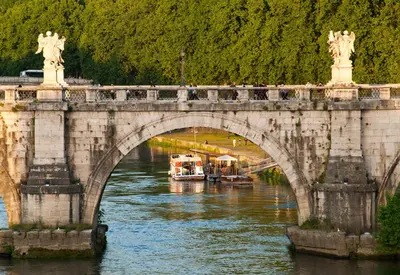 a bridge over a river with a boat at Rome Services Porta Castello in Rome