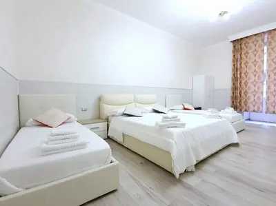 two beds in a bedroom with white walls and wooden floors at Oscar suite home in Rome