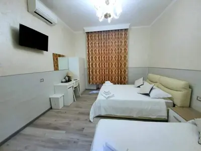a white bedroom with two beds and a television at Oscar suite home in Rome
