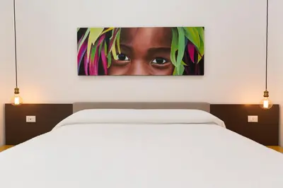 a painting of a woman is hanging above a bed at B & Bea in Rome