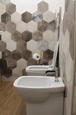 a bathroom with a toilet and a tiled wall at Nannarè Guest House in Rome