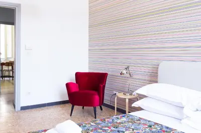 a bedroom with a red chair next to a bed at TrastevereHome - San Cosimato View on Trastevere Square in Rome