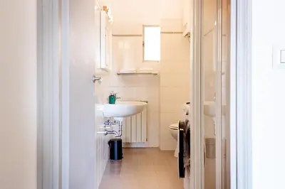 a white bathroom with a sink and a toilet at TrastevereHome - San Cosimato View on Trastevere Square in Rome