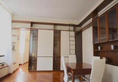 a dining room with a wooden table and white chairs at Trevi Nice Holiday - Luxury Apartment in Rome