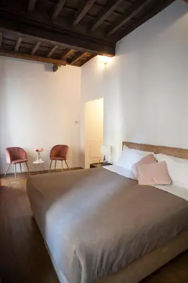 a bedroom with a large bed and two chairs at Palazzetto de Lante Appartamento Pinta in Rome