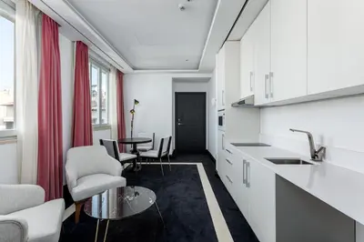 a kitchen with white cabinets and a table and chairs at Room Mate Collection Gran Filippo, Rome-Fontana di Trevi in Rome