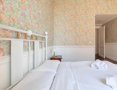 a white bed in a bedroom with floral wallpaper at B&b Querini in Rome