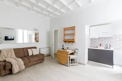a living room with a couch and a table and a kitchen at A World Aparts - 61 Margutta in Rome