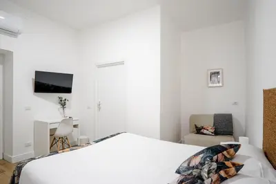 a white bedroom with a bed and a chair at Da Fede in Rome