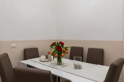 a white table with a vase of flowers on it at A World Aparts - 55 Palermo in Rome