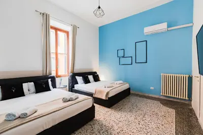 a bedroom with two beds and a blue wall at A World Aparts - 55 Palermo in Rome