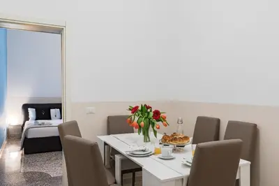a dining room with a white table with a vase of flowers at A World Aparts - 55 Palermo in Rome