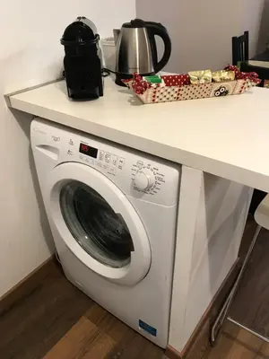 a white washing machine sitting under a counter at Trastevere Sweet Home in Rome