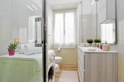 a bathroom with a washing machine next to a toilet at Martino Delightful Apartment in Rome