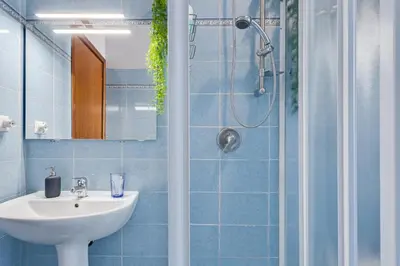 a blue bathroom with a sink and a shower at St. Joseph Apartment 47 in Rome
