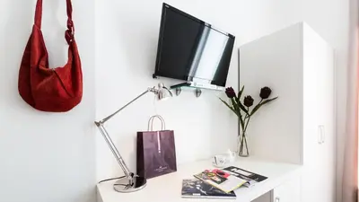 a desk with a television and a red purse on a wall at Rest Guesthouse in Rome