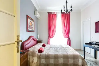 a bedroom with a bed and a window with red curtains at B&B Calamatta in Rome