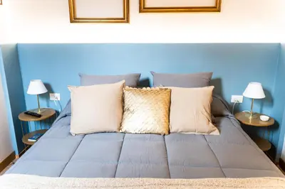 a blue bedroom with a bed with pillows and two lamps at Arc Trilussa 44 in Rome