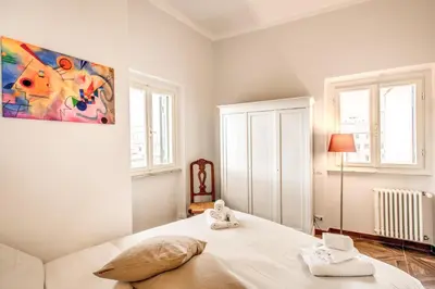 a bedroom with a white bed with a painting on the wall at Cavour Attic with terrace in Rome