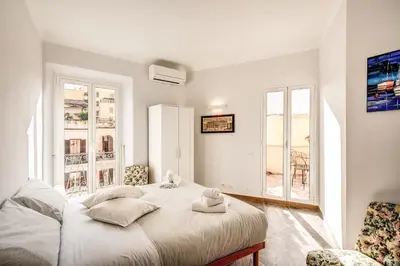 a white bedroom with a bed and two windows at Cavour Attic with terrace in Rome