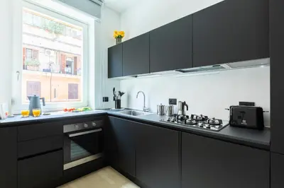 a kitchen with black cabinets and a sink and a window at ROMAC Trinity - 3bdr apartment with Sauna & Jacuzzi in Campo de Fiori in Rome