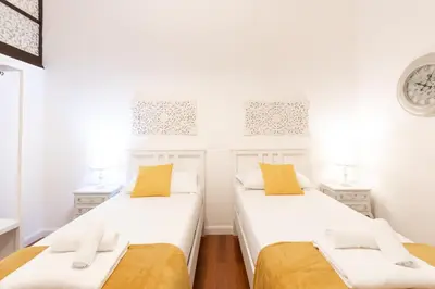 two beds in a room with white walls and yellow pillows at Leonardo Suite Pantheon in Rome