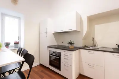 a kitchen with white cabinets and a sink and a table at Leonardo Suite Pantheon in Rome