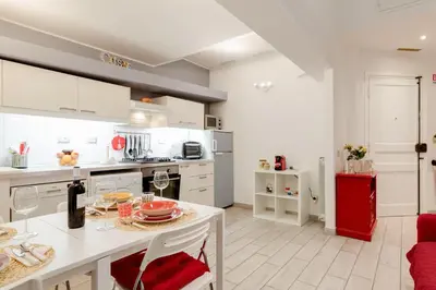 a kitchen with white cabinets and a red refrigerator at Trastevere In Love in Rome