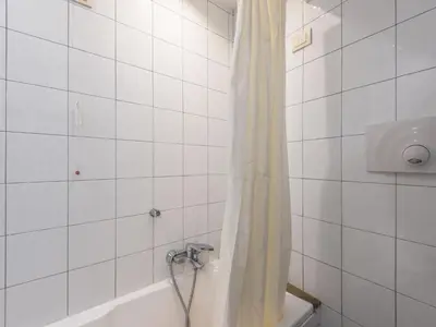 a white tiled bathroom with a shower curtain and a tub at Apartment Antico Balcone by Interhome in Rome