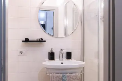 a white bathroom with a sink and a mirror at A Casa Lamperini 59 in Rome