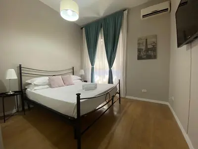 a bedroom with a bed with white sheets and pink pillows at èROMA - RE DI ROMA Apartment in Rome