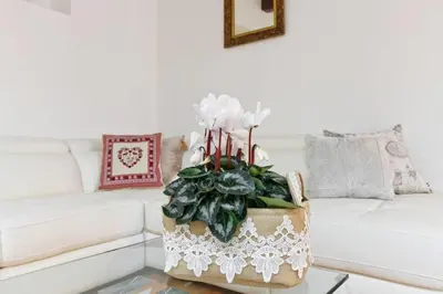 a living room with a white couch and a table with a plant at La Finestra su Trastevere - Appartamento 100 mq Centrale, Luminoso, Spazioso in Rome