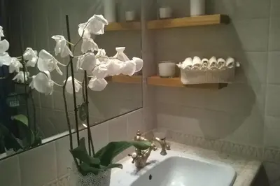 a bathroom with a sink and a mirror and white flowers at La Finestra su Trastevere - Appartamento 100 mq Centrale, Luminoso, Spazioso in Rome