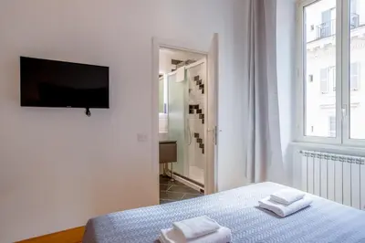 a white bedroom with a bed and a television at New Unico San Cosimato in Rome