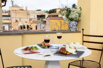a table with food and glasses of wine on a balcony at Poēsis Experience Hotel in Rome