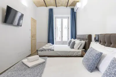 a bedroom with two beds and a tv on a wall at Industrial-Style Apartment Next To Vatican Metro in Rome