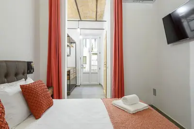 a bedroom with a white bed with red curtains at Industrial-Style Apartment Next To Vatican Metro in Rome