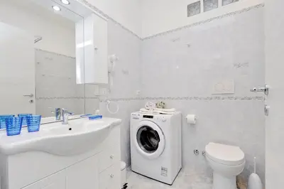 a white bathroom with a washing machine and a sink at GEMMA DOMUS in Rome