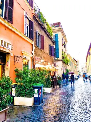 a city street in the rain with people walking down the street at Romantico appartamento a Trastevere in Rome