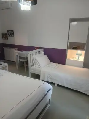 a bedroom with two beds and a table and a mirror at Stefano House Vaticano Roma in Rome