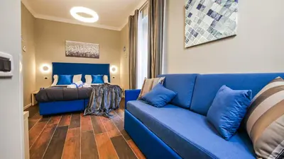 a living room with a blue couch and a bed at Home Suites Giolitti in Rome