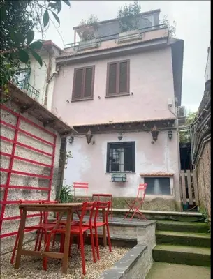 a group of red chairs and a table in front of a house at Casa Flavia - Beauty apartment close to Vatican Museum in Rome