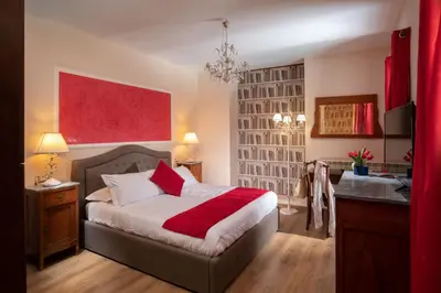 a bedroom with a bed with a red blanket and a desk at Residenza Nobile Laurina in Rome