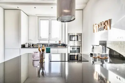 a kitchen with white cabinets and a black counter top at St. Peter penthouse in Rome