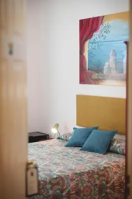 a bedroom with a bed with blue pillows and a painting at Le Tare B&B in Rome