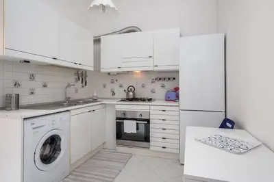 a kitchen with white cabinets and a washer and dryer at Tizy & Toto's apartment near Vatican in Rome
