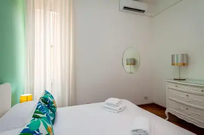 a white bedroom with a bed and a dresser at Tizy & Toto's apartment near Vatican in Rome