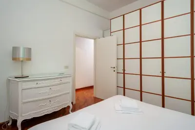a white bedroom with a bed and a dresser at Tizy & Toto's apartment near Vatican in Rome