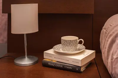 a table with a lamp and a cup on top of books at 8 HOME in Rome