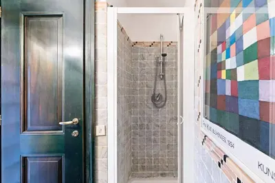 a bathroom with a shower and a black door at Appartamento via del Teatro Pace in Rome